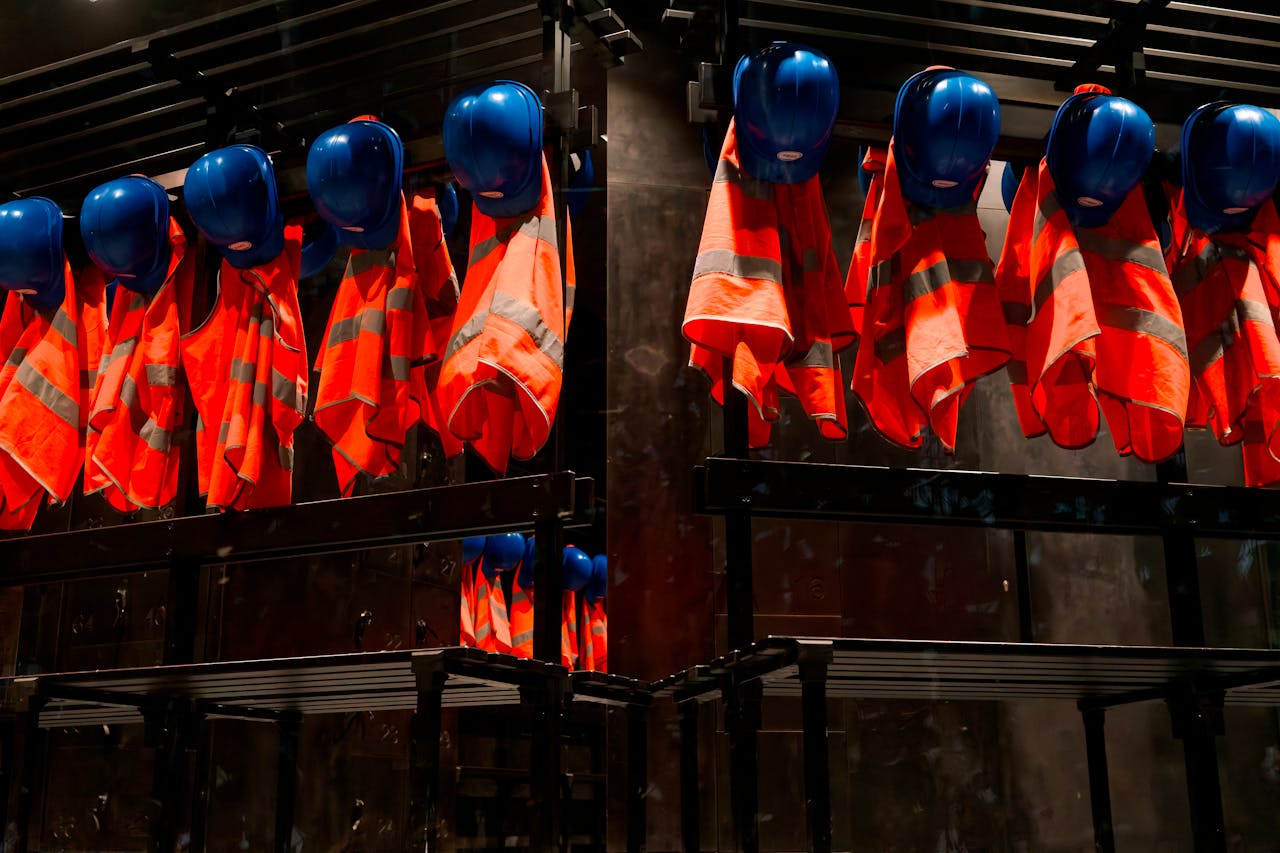 services-03 Row of orange safety vests and blue helmets hanging in industrial setting